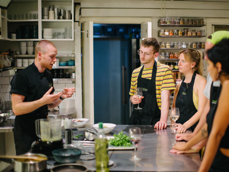 A group of people listening to a chef at a cooking class.